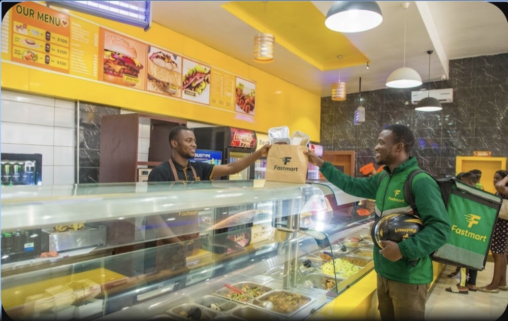 A FastMart rider collecting a packed food order at a restaurant counter.